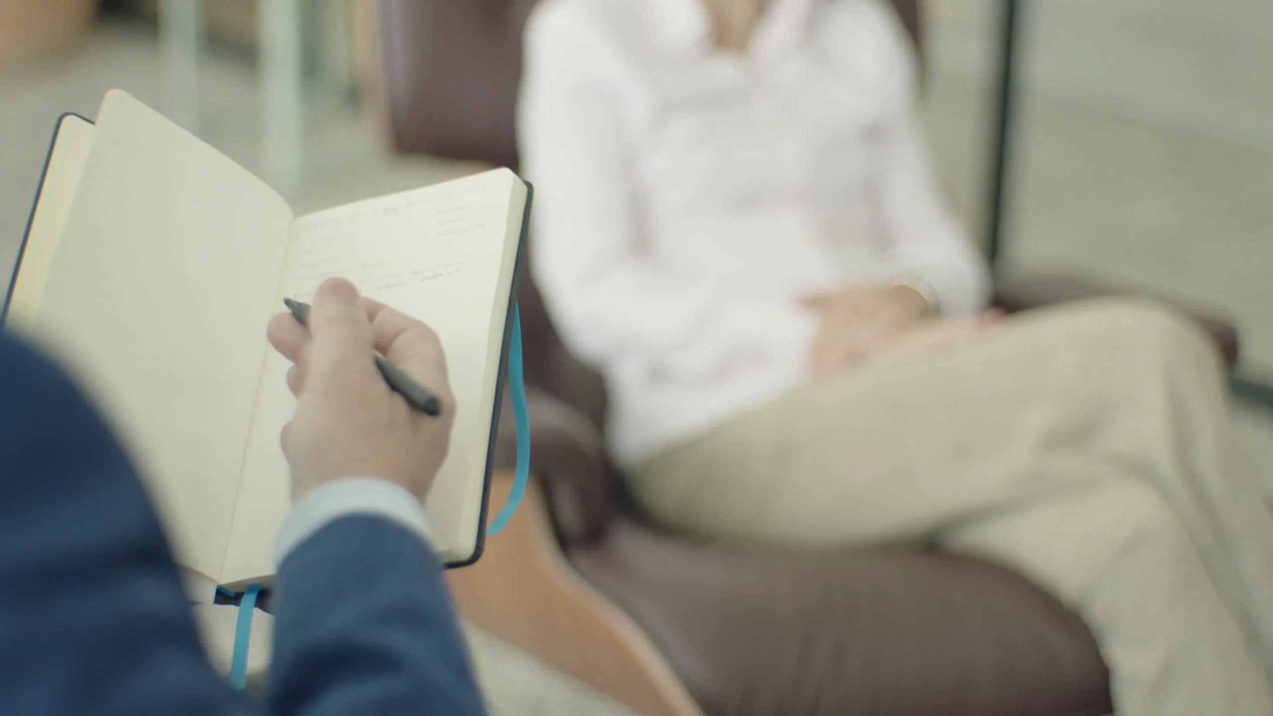 Therapist taking notes during a counseling session with a client.